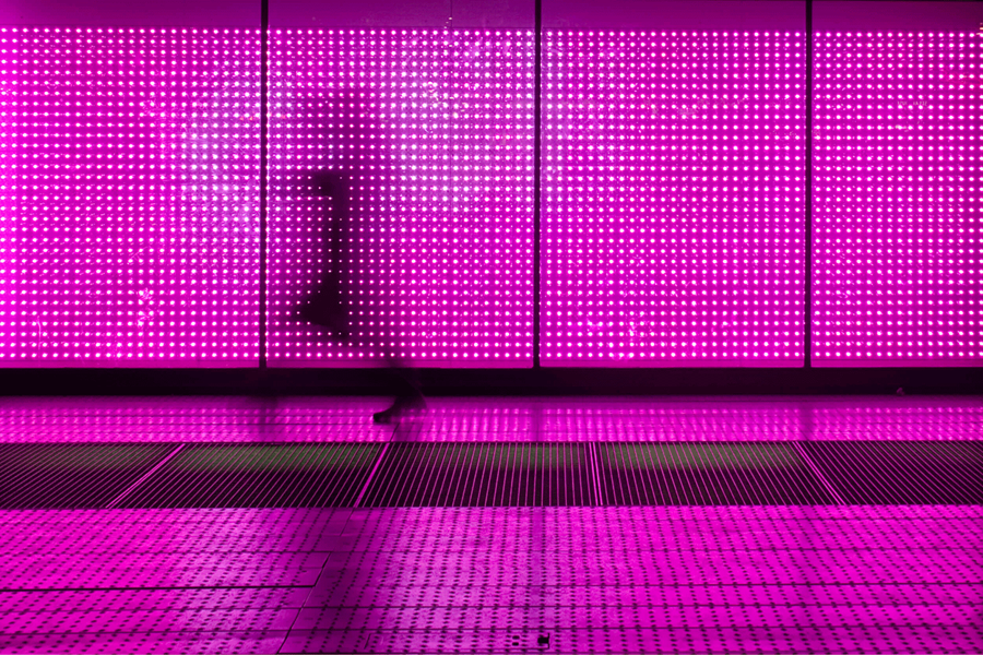 person walking in front of a light wall