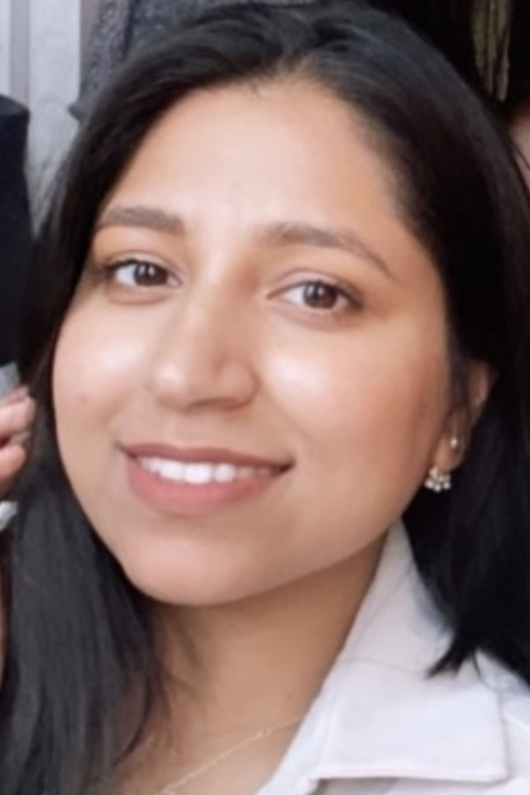 A young woman with long brown hair wearing a white jacket.