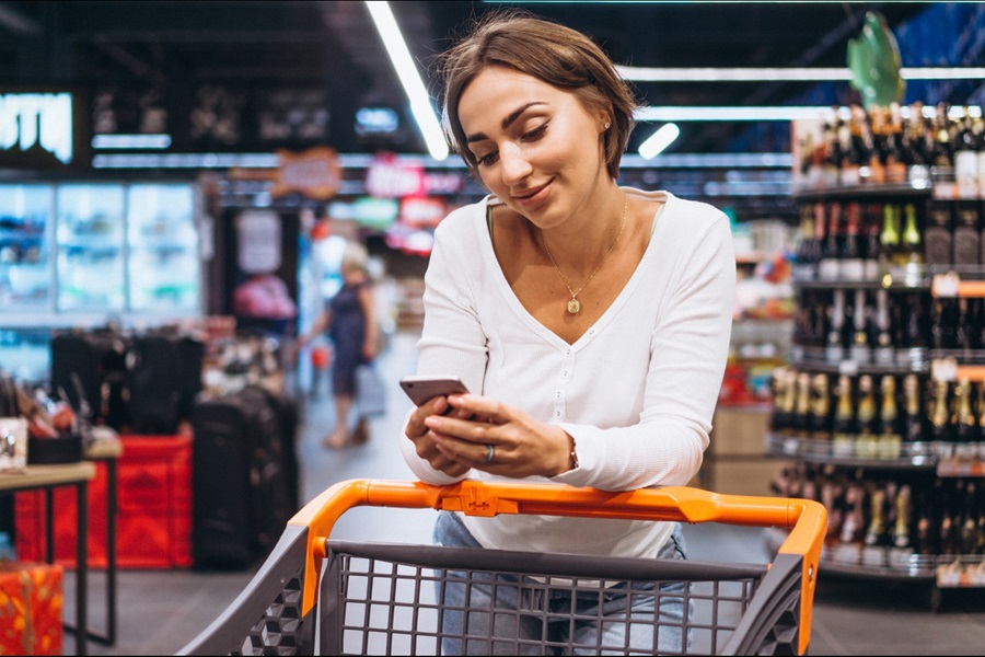 mujer consultando su teléfono en el supermercado