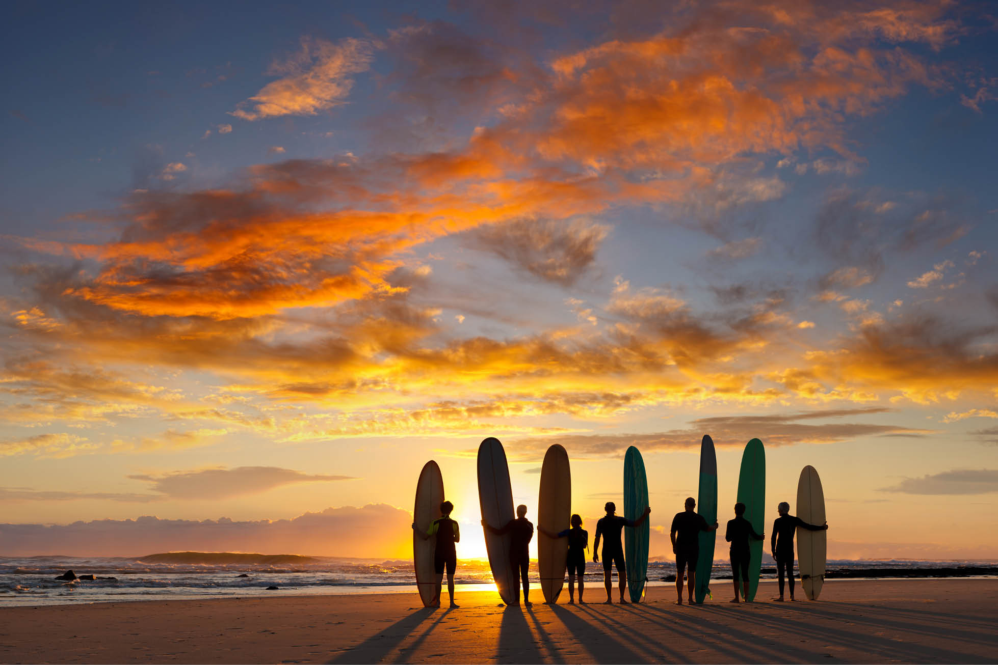 surfers seen against a sunset